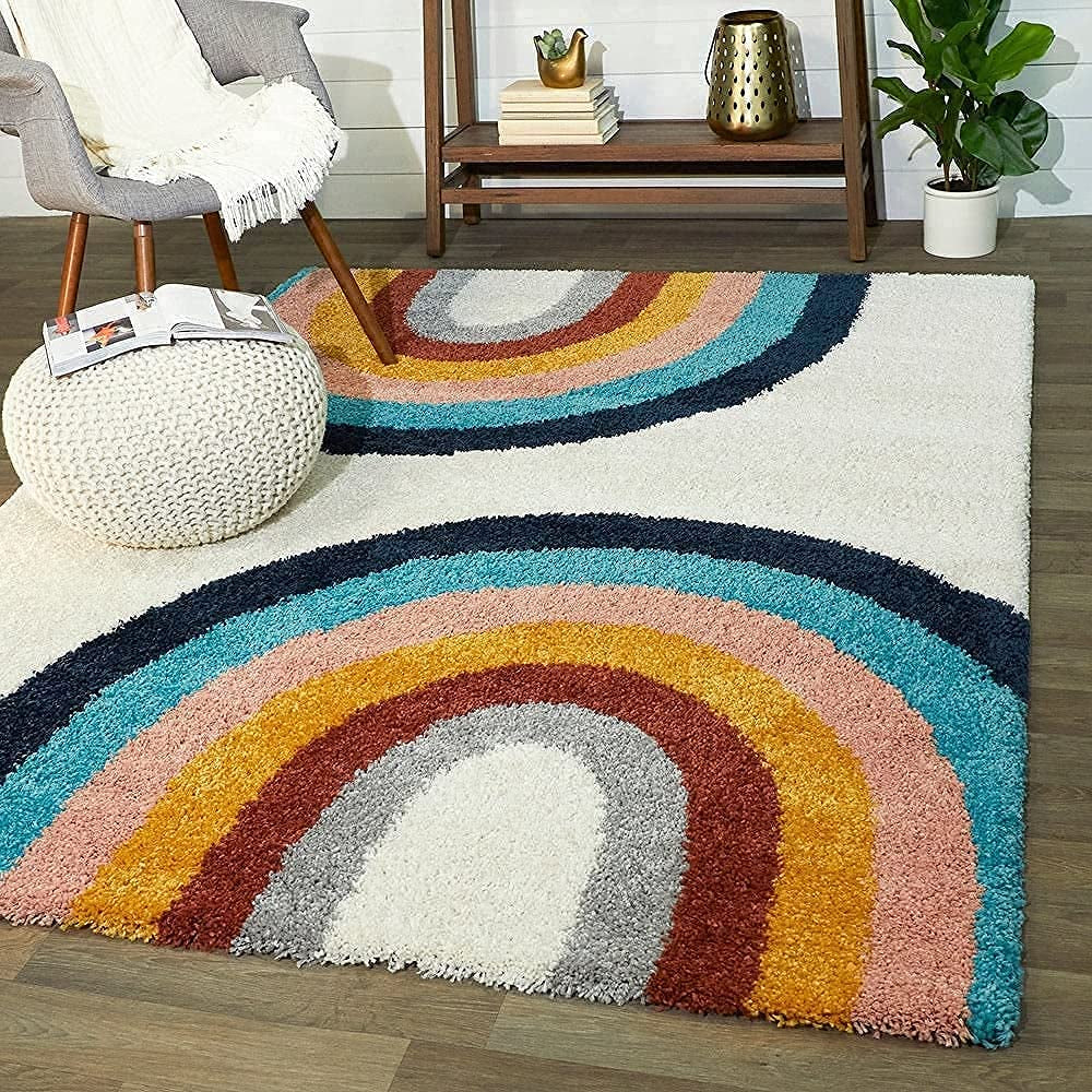 Multicolored shaggy rug with rainbow pattern on a wooden floor, surrounded by furniture and decor.