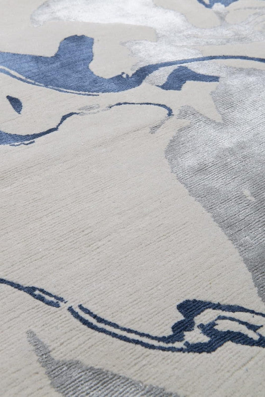 Close-up of a textured rug with abstract blue and gray patterns on a light background