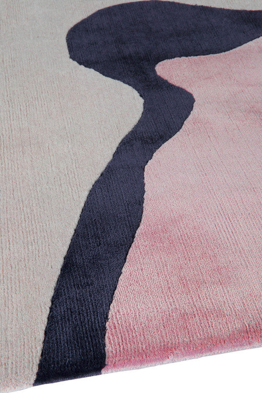 Close-up of a rug with abstract design in pink and navy on a neutral background