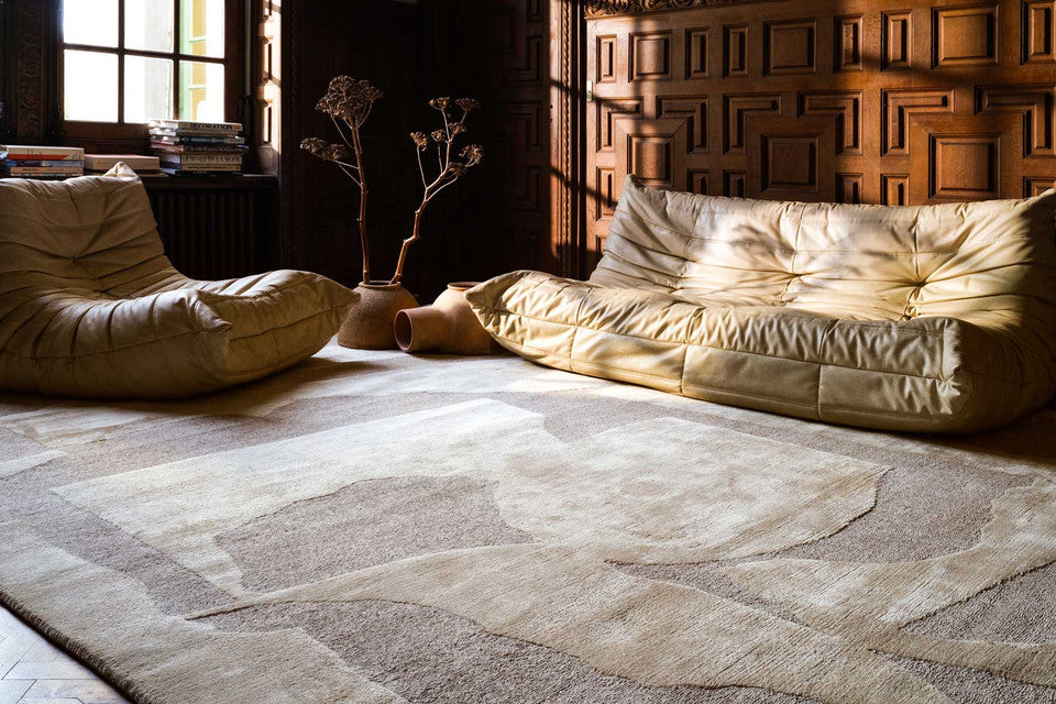 Living room with beige bean bags and a patterned rug.