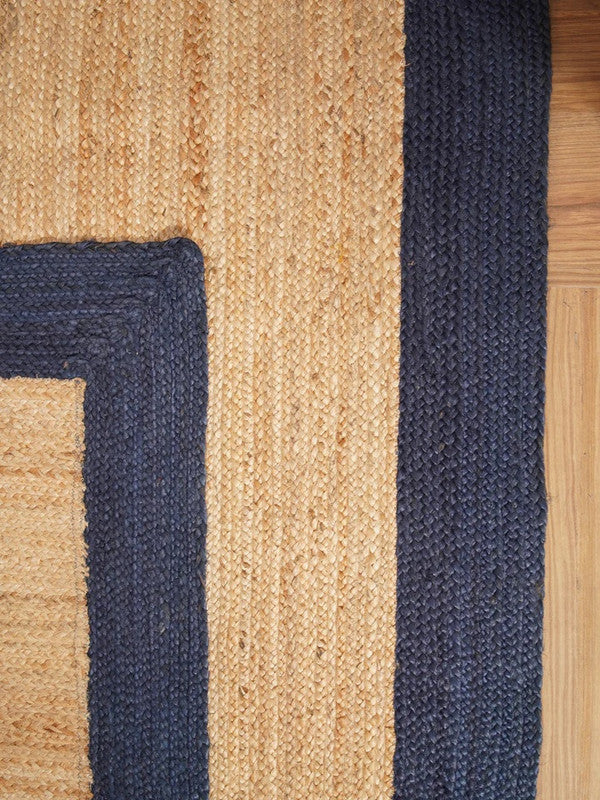 Close-up of a woven rug with blue and beige stripes on a wooden floor.