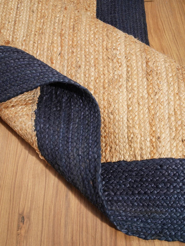 Close-up of a jute rug with blue and beige pattern on a wooden floor.