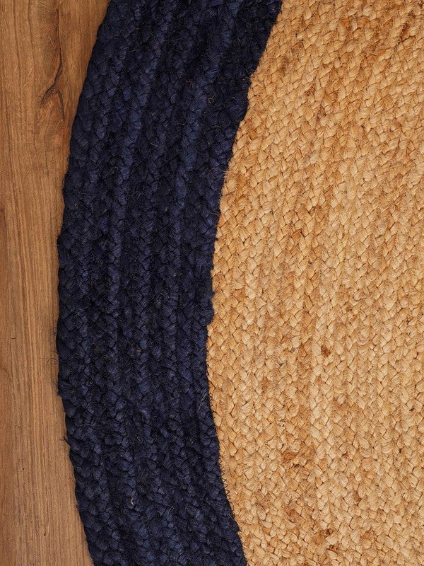 Close-up of a navy blue textured rug and a beige woven rug on a wooden floor.