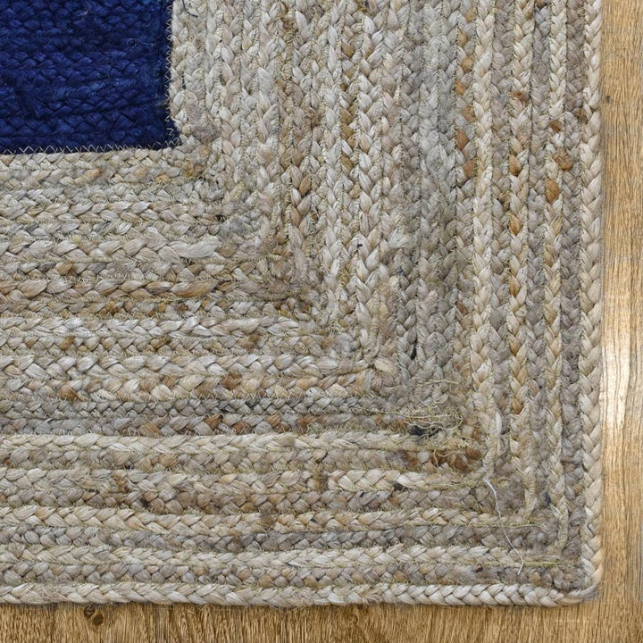 Close-up of a textured beige rug corner on a wooden floor